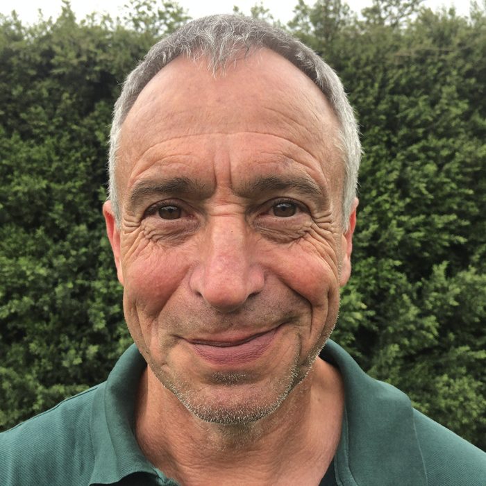 Porträtfoto von Thomas, lächelnder älterer Mann im grünen Poloshirt